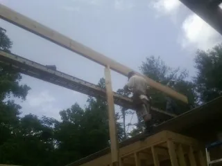 Carpenter setting a ridge beam over a new addition frame — Ice Dam Removal by Roofing Brothers in Bellefonte
