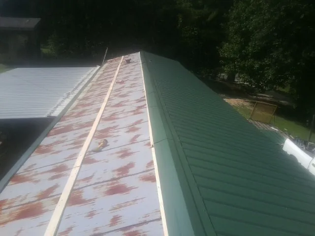 Old rusted panels beside newly installed green metal roofing — Wind Damage Roof Repair by Roofing Brothers in Bellefonte