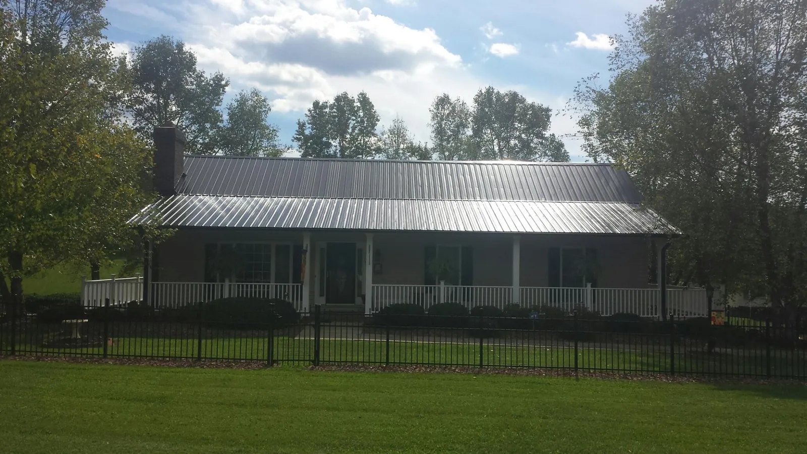 Gray metal roof on a brick ranch with a full width front porch — Gutter Guard Installation work by our crew in Bellefonte