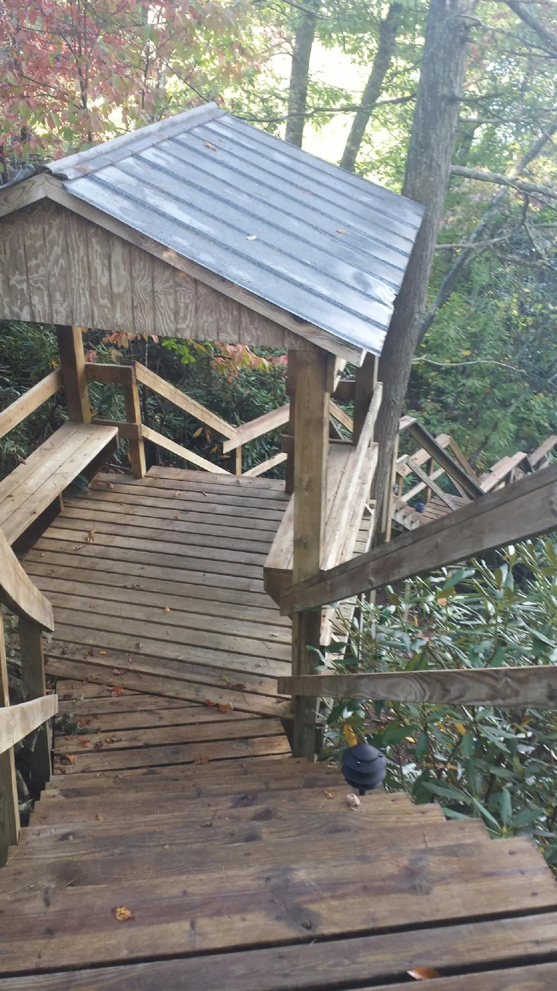 Metal roofed shelter over wooden steps on a wooded walkway — Skylight Repair & Installation work by our crew in Bellefonte