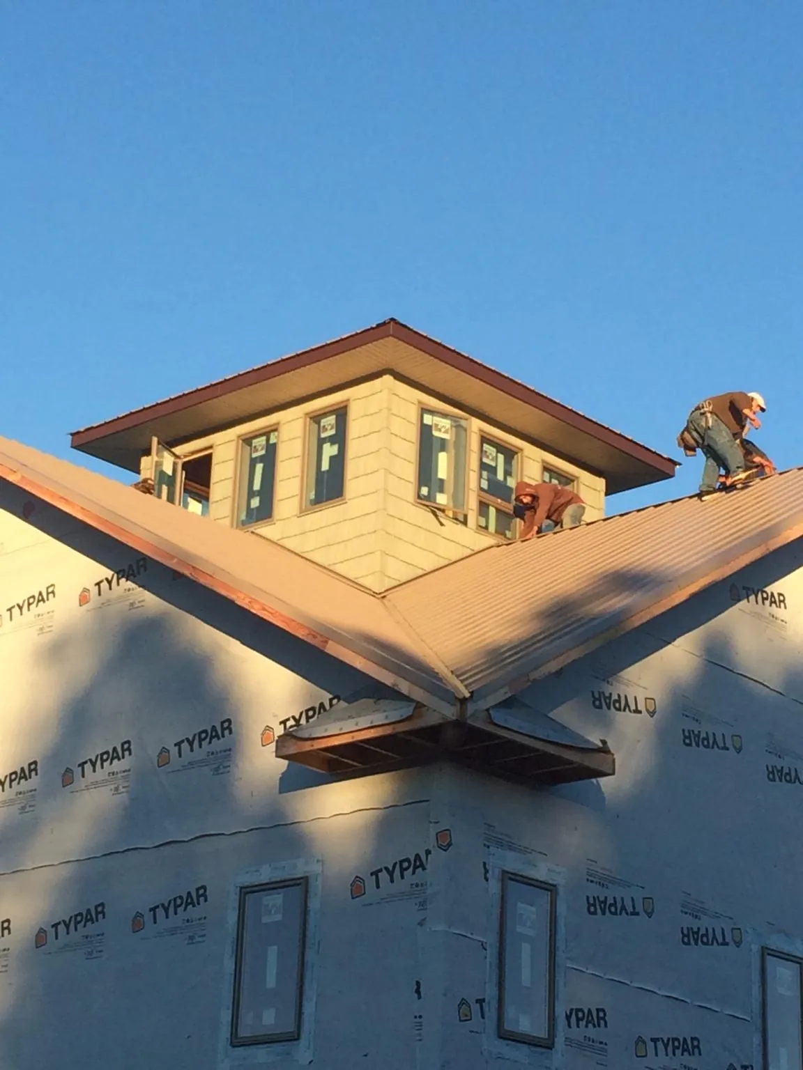 Roofers working around a rooftop cupola on a new metal roof at sunset — Roof Waterproofing in Bellefonte by Roofing Brothers